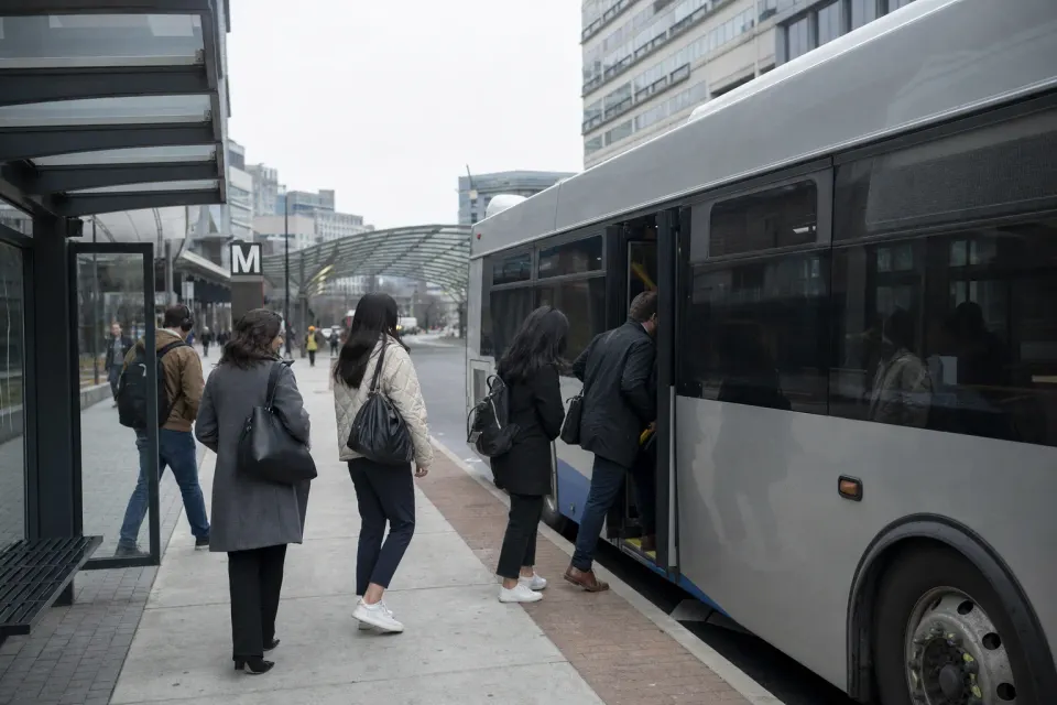 Commuters boarding a bus at a covered stop near a Tysons transit station