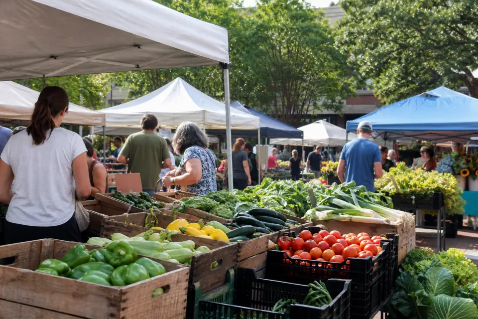 Shoppers browsing produce beneath canopy tents at a weekend farmers market