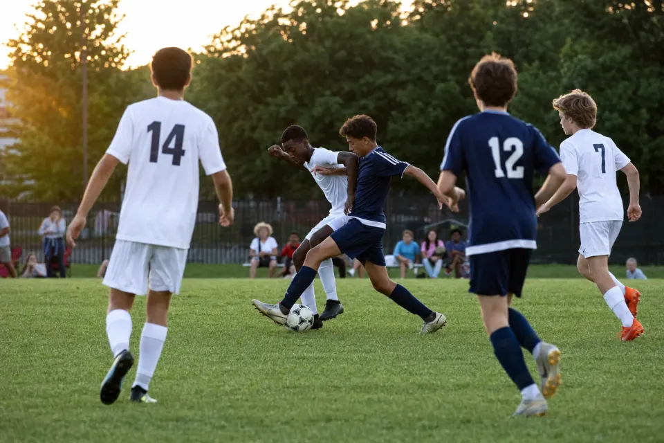 Youth soccer players contesting the ball during an evening community match
